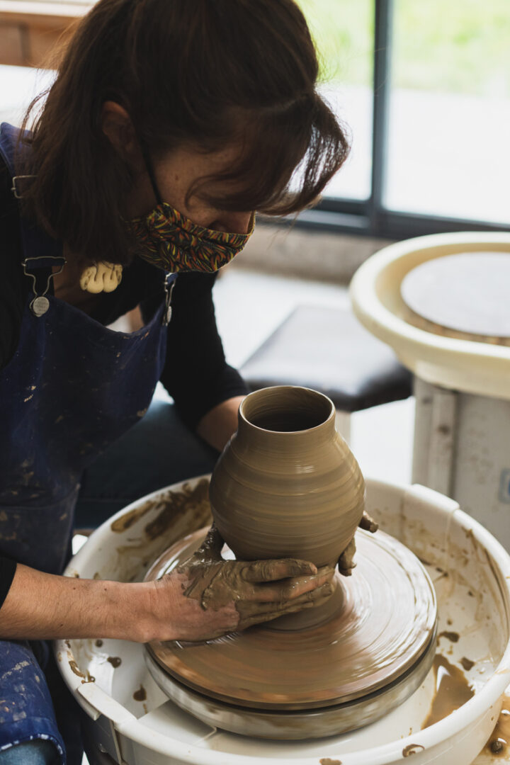 une femme tourne un vase dans un atelier