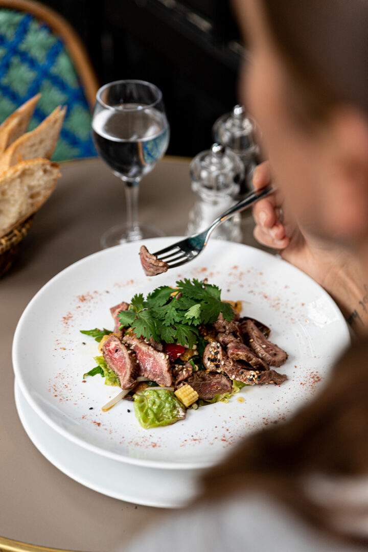 Une femme mange une salade de boeuf dans un restaurant parisien