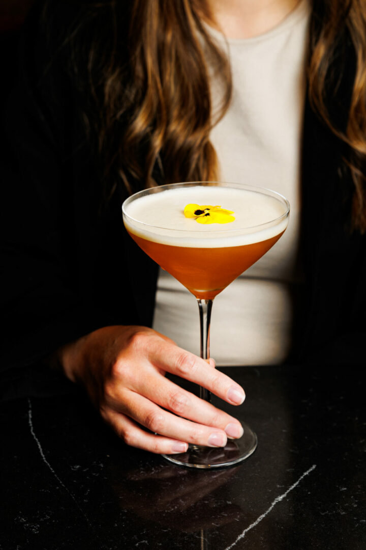 Une femme tient un cocktail dans sa main.