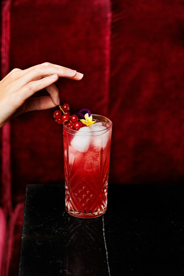 Une femme dépose un fruit sur un cocktail.